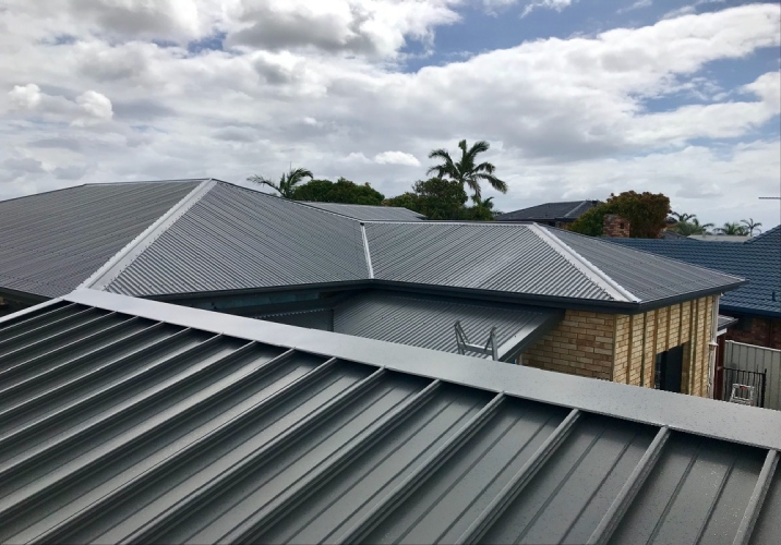 Dark grey colorbond roof of a single storey house on an overcast day.