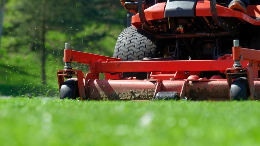 a red lawnmower mowing a lawn