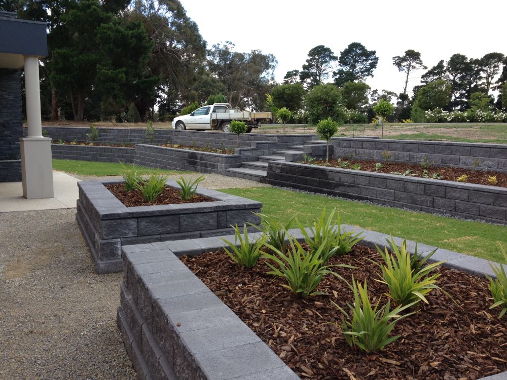 A front yard with small enclosed gardens containing mulch and plants